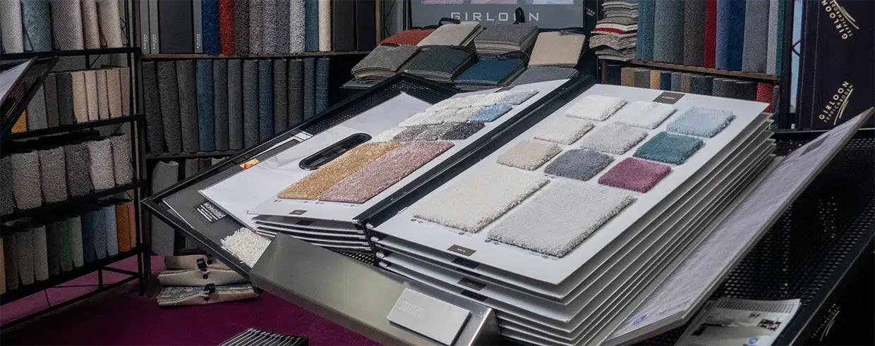 Erkunden Sie unseren Bereich „Über Uns“ im Ausstellungsraum. Dort finden Sie eine kuratierte Ausstellung von Teppichmustern in den unterschiedlichsten Farben und Texturen, die alle sorgfältig auf Gestellen und Paneelen für Ihre Besichtigung angeordnet sind. - T&K WOHNSTDIO - Raumausstattung, Bodenbeläge, Vinylboden, Parkett, Gardinen - Saarburger Straße 25, 67071 Ludwigshafen